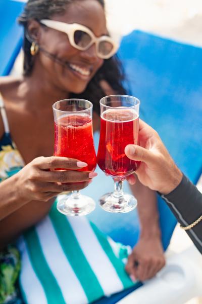 Couple cheers with red drink on beach