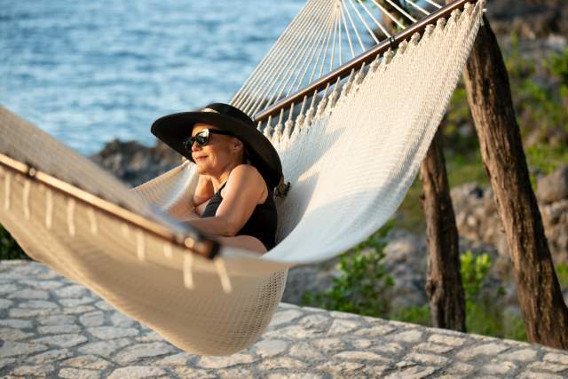 Woman relaxing in hammock overlooking water